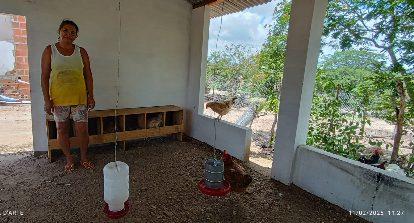 Agricultora pousa para foto diante do seu galinheiro recém construído