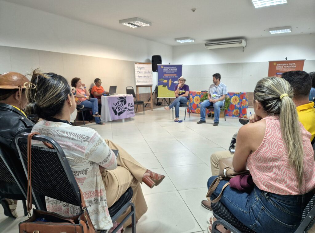 Na foto, uma grupo de pessoas reunidas em círculo conversam sobre o P1+2