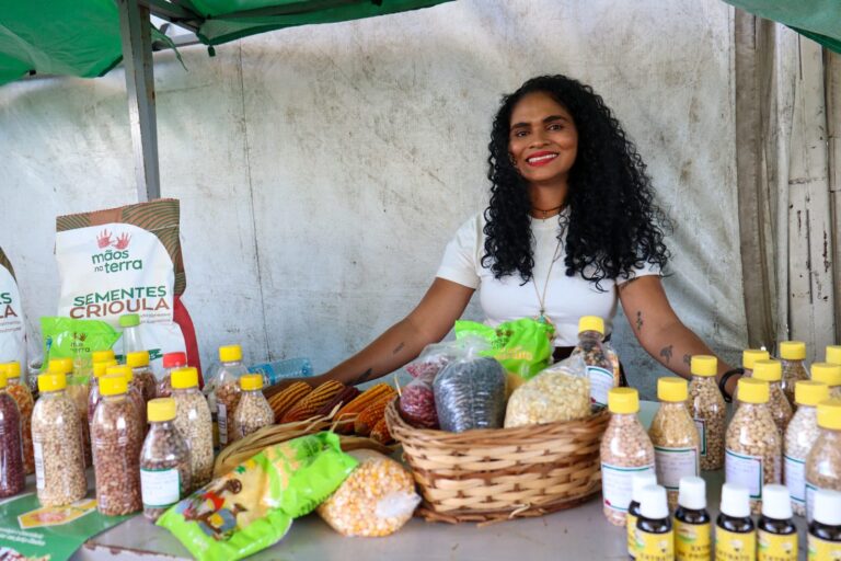 Jovem atrás de uma mesa com sementes crioulas.