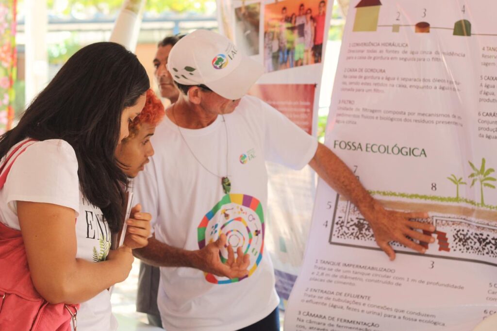 Na foto vemos uma agricultora explicando para a outra um banner durante o Terreiro de Inovações Camponesa.
