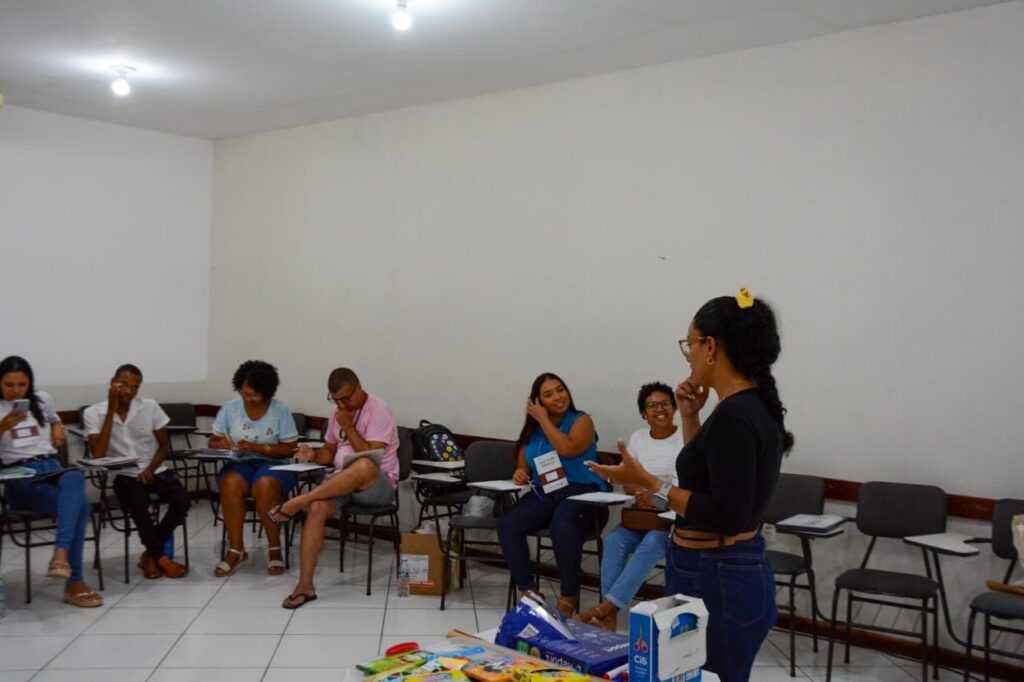 Na foto, Mariana Sebastião, do Núcleo de Comunicação e Disseminação Científica do Cidacs, fala para outras pessoas, sentadas em roda.